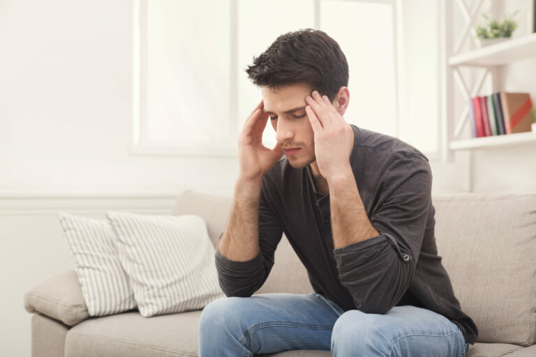 Person mit Kopfschmerzen auf der Couch